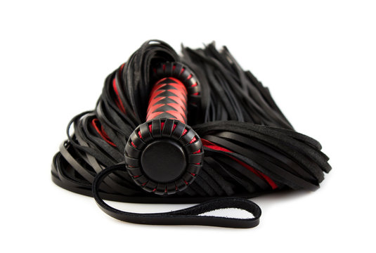 Red-black floger with a patterned handle and leather tails on white background.concept of pleasure from pain