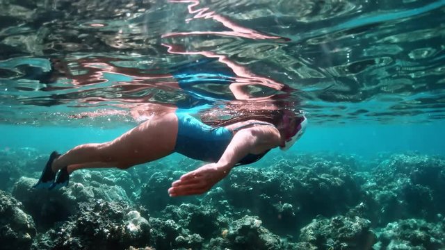 Young lady snorkeling over coral reefs in a tropical sea. Woman with mask snorkeling in clear water.