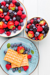 Fresh berry salad on blue dishes. Vintage wooden background.