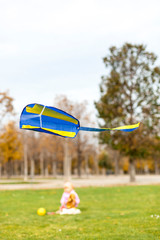 Flying child kite with kid in background. Kleiner Winddrachen mit Kind im Hintergrund.