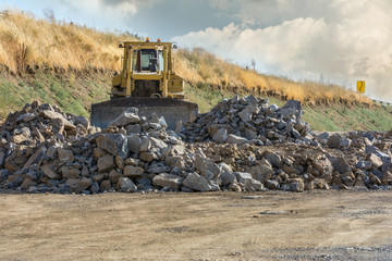 Excavator moving stone on construction works of a road