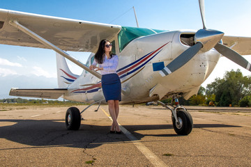 Beautiful young Asian girl sitting on the wheel of an airplane