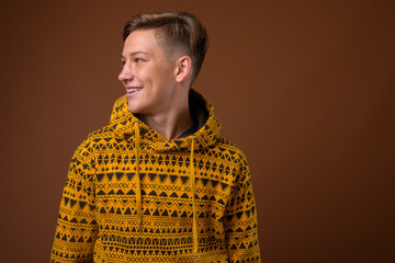 Fototapeta premium Studio shot of young handsome teenage boy against brown backgrou