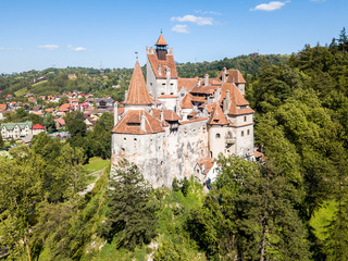 Obraz premium Bran castle on a hill with high spires, walls, red tiled roofs, surrounded by Bran town, Wallachia, Transylvania, Romania. Known as Dracula's Castle
