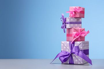 Collection of Christmas gifts in boxes with ribbons on light blue background. Copy space.