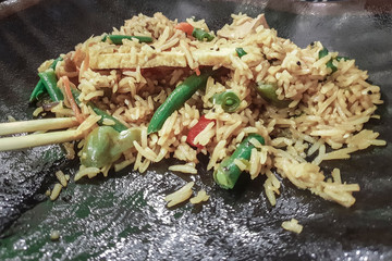 Rice with green beans and pepper on a black plate, close-up