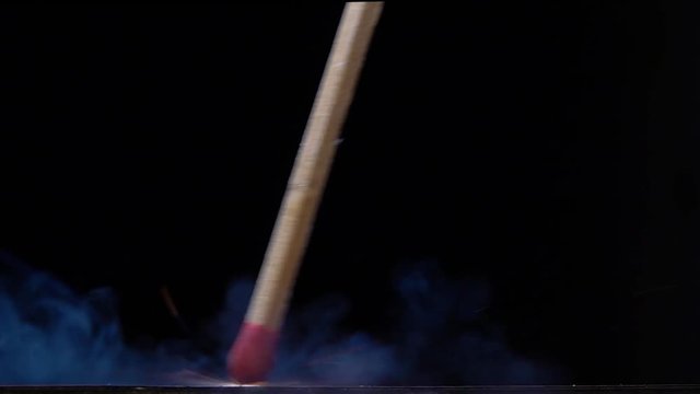 A matchstick lights after it is struck against the striking surface of a match box. Slow motion
