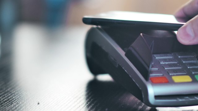 Contactless payment with smartphone with NFC technlogy. Paying with a smartphone device on a credit card POS terminal. Wireless payment.