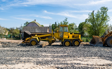 Yellow loader with empty bucket stands on a stone gravel during road construction works. The stones for the road. Unloading stone.