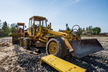 Yellow loader with empty bucket stands on a stone gravel during road construction works. The stones for the road. Unloading stone.