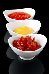 Sauce in a white bowl on a black background with reflection.