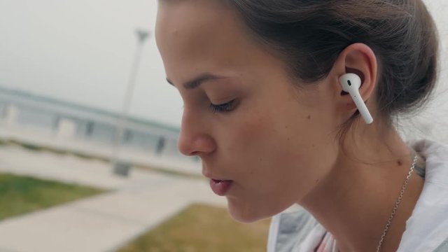 Young woman using tablet outdoor laying on grass, smiling. student after university in campus girl in airpods headphones earpods happy homework