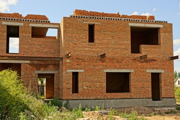 Fototapeta premium large unfinished brown brick house in green grass