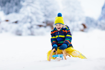 Boy on sled ride. Child sledding. Kid on sledge