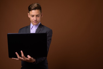 Studio shot of young handsome businessman against brown backgrou
