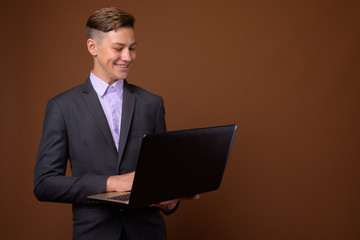 Studio shot of young handsome businessman against brown backgrou