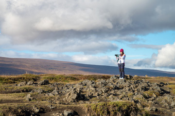 A tourist girl take photo mountain valley near godafoss waterfall, Iceland