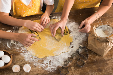 partial view of child with mother and grandmother preparing cookies together in kitchen