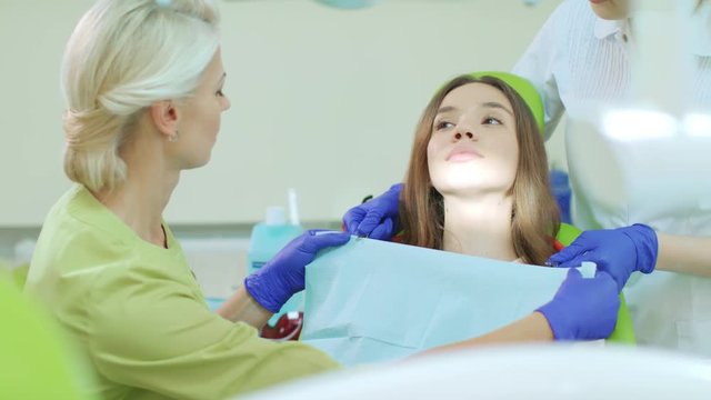 Dentist with assistant preparing for dental treatment. Patient with toothache sitting in dentist chair. Professional stomatology specialist in dentist office