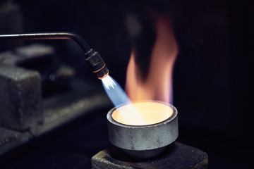 Goldene Flamme mit Bunsenbrenner beim Erhitzen einer Schale beim Goldschmied