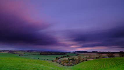 Fototapeta na wymiar Long shutter speed of colourful autumn sunset over valley of Hambledon looking towards Broad Halfpenny Down, on the edge of the South Downs National Park, Hampshire, UK