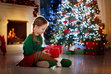 Kids at Christmas tree. Children open presents