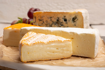 Tasting plate with four France cheeses, cream brie, marcaire, saint paulin and blue auvergne cheese, served with fresh ripe grapes