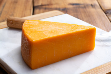 Piece of bright yellow hard cheese cheddar, originating in the English village of Cheddar in Somerset