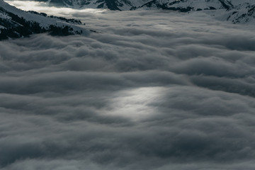 Ski slopes on the hills of Austrian Alps above clouds