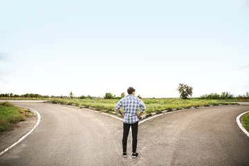 Fotobehang Young man standing at crossroads. Concept of choice © Pixel-Shot