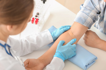 Doctor sticking adhesive plaster on patient's hand in hospital