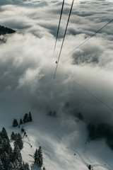 Cable lift in clouds in Austrian Alps mountains above ski slope