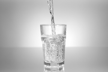 Pouring of water in glass on table
