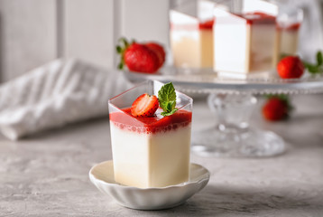 Glass with tasty strawberry panna cotta on grey table