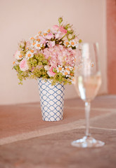 Romantischer Blumenstrauß und ein Sektglas, der ideale Hintergrund für Deine Hochzeitseinladung