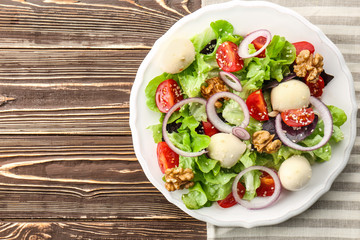 Delicious fresh salad with walnuts on wooden table