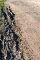 Muddy ground after rain. Extreme path rural dirt road in the hills. Wheel Off-road track in a countryside landscape with a muddy road.