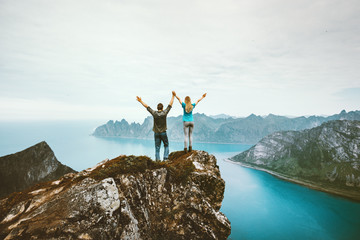 Couple friends traveling together on cliff edge in Norway man and woman family healthy lifestyle...