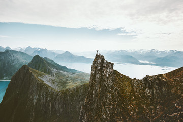 Norway mountaineering travel man standing on cliff mountain top above fjord adventure climbing...