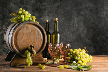 Barrel and glassware with wine and ripe grapes on wooden table