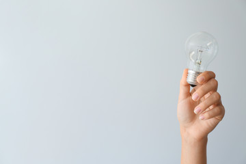 Female hand with eco light bulb on light background