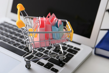 Small cart and laptop on table. Internet shopping concept