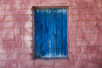 Fototapeta na wymiar ventana azul de madera en pared de ladrillo rosa salmón