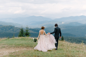 Beautifull wedding couple kissing and embracing near the shore of a mountain river with stones