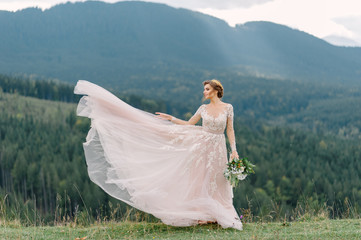 Fototapeta na wymiar whirling bride holding veil skirt of wedding dress at pine forest