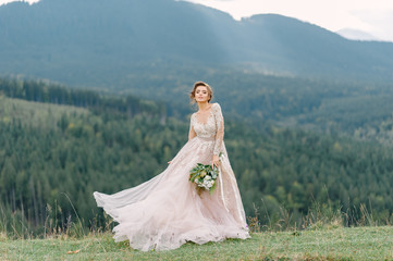 whirling bride holding veil skirt of wedding dress at pine forest