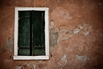 Fototapeta na wymiar pared de color teja y contraventana verde corroida por la humedad de las calles de venecia