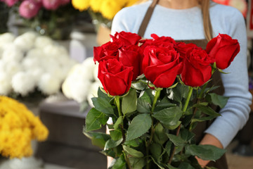 Saleswoman holding bouquet of beautiful roses in shop