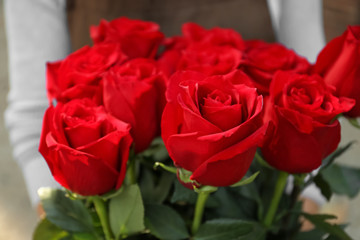 Saleswoman holding bouquet of beautiful roses, closeup