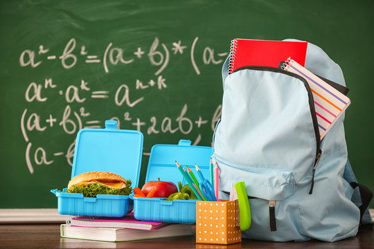 Backpack with school supplies and lunch box near chalkboard